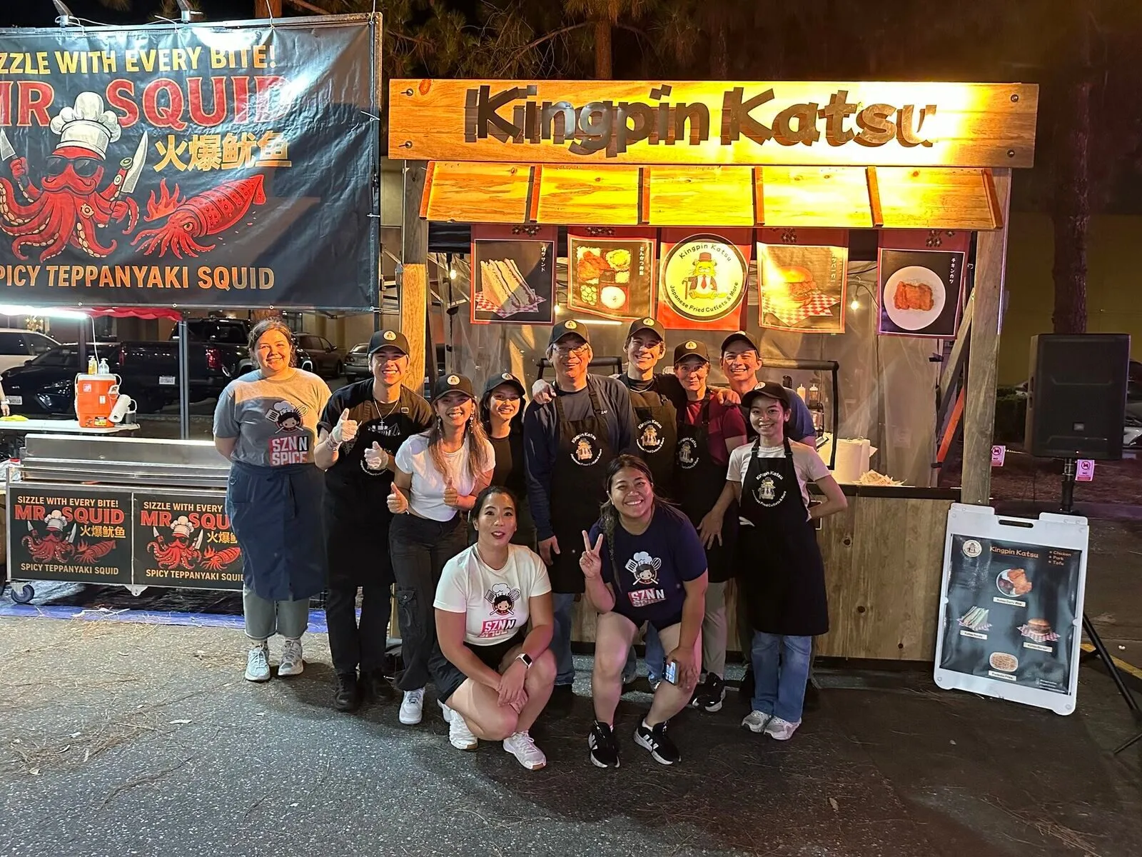The Kingpin Katsu crew in front of their wooden pop-up booth at night